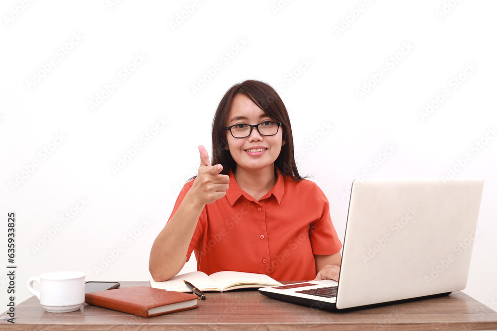 Optimistic young asian entrepreneur woman sitting with laptop on the desk while pointing on you Optimistic young asian entrepreneur woman sitting with laptop on the desk while pointing on you