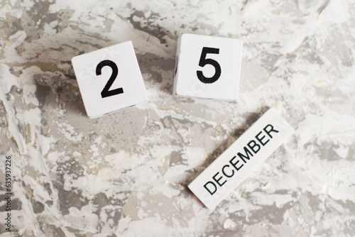 Flatlay, wooden calendar with the date December 25 on a white textured background. Christmas is coming soon.