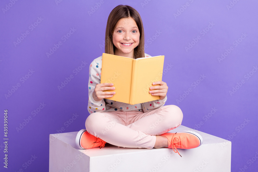 Photo of positive shiny little girl dressed dotted pullover reading interesting book isolated purple color background Photo of positive shiny little girl dressed dotted pullover reading interesting book isolated purple color background