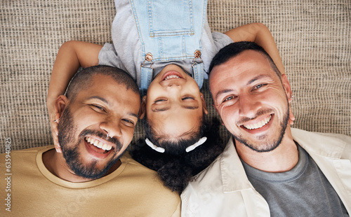 Gay dad, blended family and foster with a girl lying together on the floor of the home for adoption from above. LGBT love, children or kids and a daughter bonding with her happy parents in the house