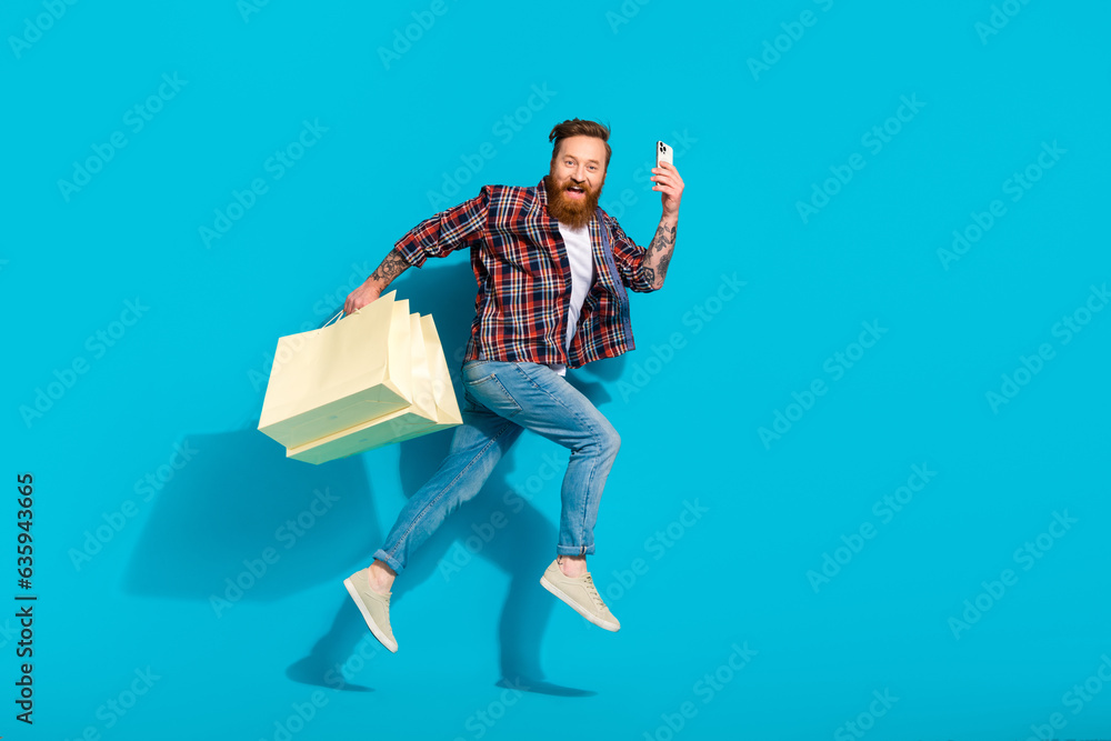 Full body photo of jumper crazy mature man red hair beard carry packages shopaholic order clothes online isolated on blue color background Full body photo of jumper crazy mature man red hair beard carry packages shopaholic order clothes online isolated on blue color background