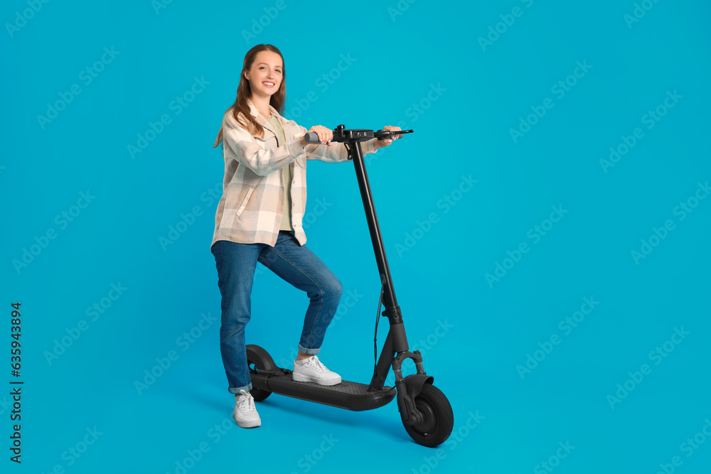 Happy woman with modern electric kick scooter on light blue background Happy woman with modern electric kick scooter on light blue background