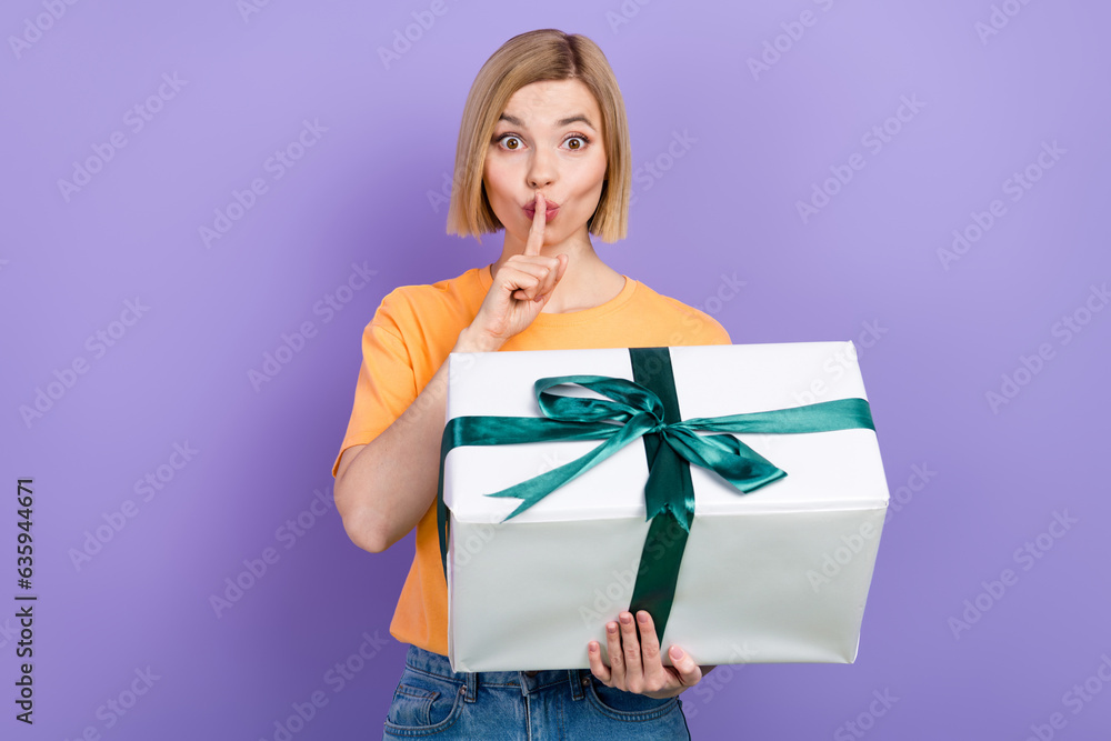 Portrait of funny adorable girl with bob hairdo dressed stylish clothes hold gift finger on lips isolated on violet color background Portrait of funny adorable girl with bob hairdo dressed stylish clothes hold gift finger on lips isolated on violet color background