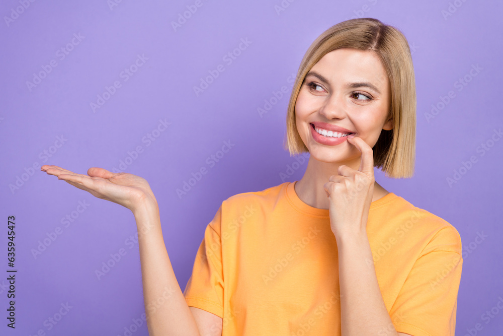 Portrait of adorable woman with bob hairdo wear stylish t-shirt presenting offer empty space finger on teeth isolated on purple background Portrait of adorable woman with bob hairdo wear stylish t-shirt presenting offer empty space finger on teeth isolated on purple background