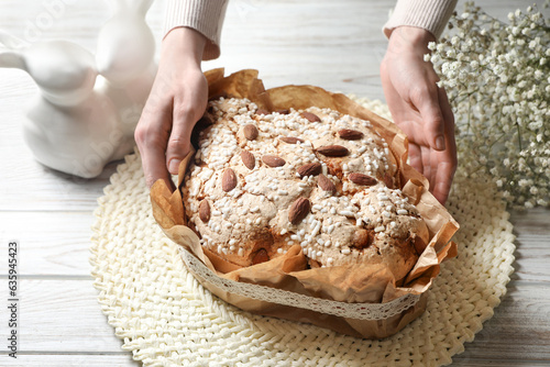 Woman with delicious Italian Easter dove cake (traditional Colomba di Pasqua) at white wooden table, closeup