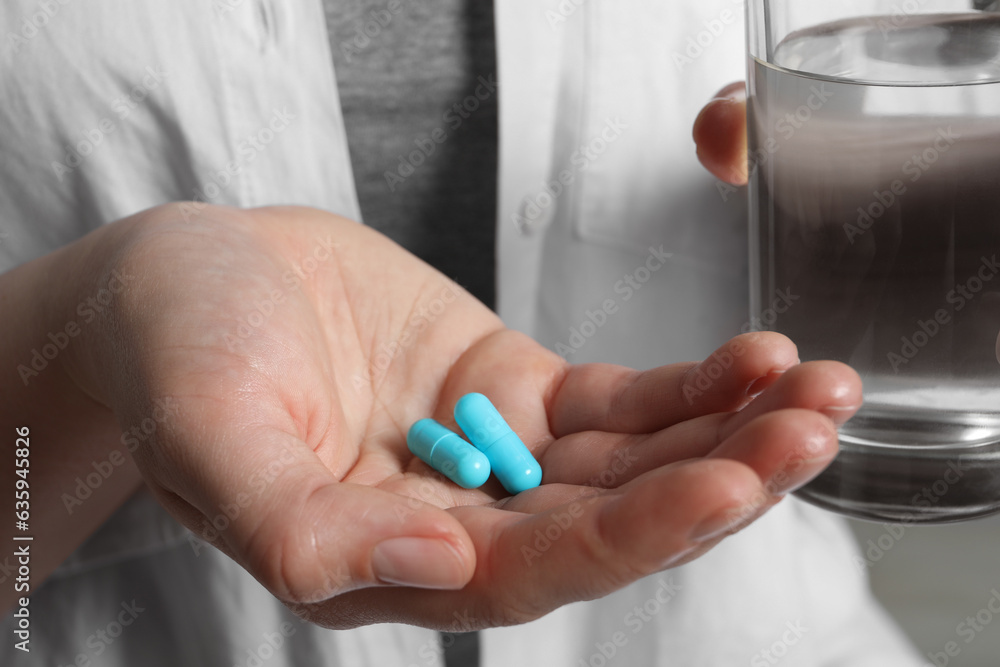 Woman with pills and glass of water, closeup Woman with pills and glass of water, closeup