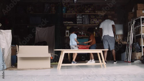 Young mixed race family cleaning up the garage and packing away tools