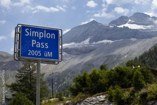 Road sign for the famous Simplon Pass in Switzerland, with height information and a background of mountains. Copy space to the right.