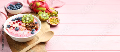 Smoothie bowl with granola, kiwi and berries on pink wooden table. Banner design with space for text