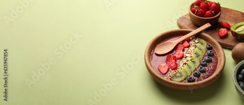 Smoothie bowl with muesli, kiwi and berries on pale green table. Banner design with space for text