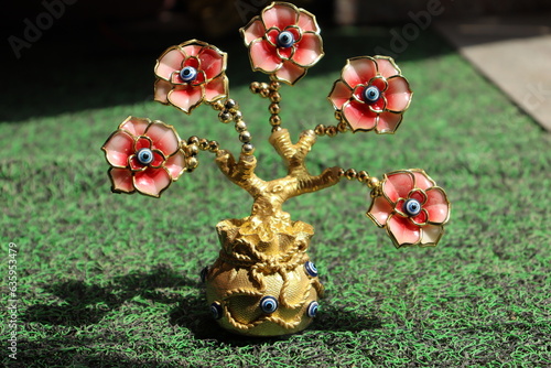 A golden Pot Devil Eye Plant with Five devil eye Flowers in harsh Sunlight on the grass carpet, Vastu or Fang sui Item