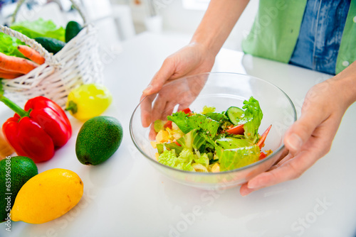 Cropped photo of young girl arms wear green shirt preparing tasty fresh salad indoors kitchen room