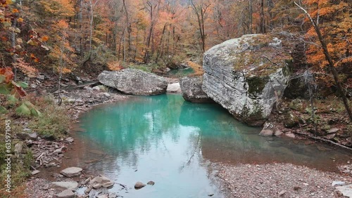 Beautiful pool of water and large boulder in Arkansas ozark mountain river via aerial drone in fall with autumn forest 