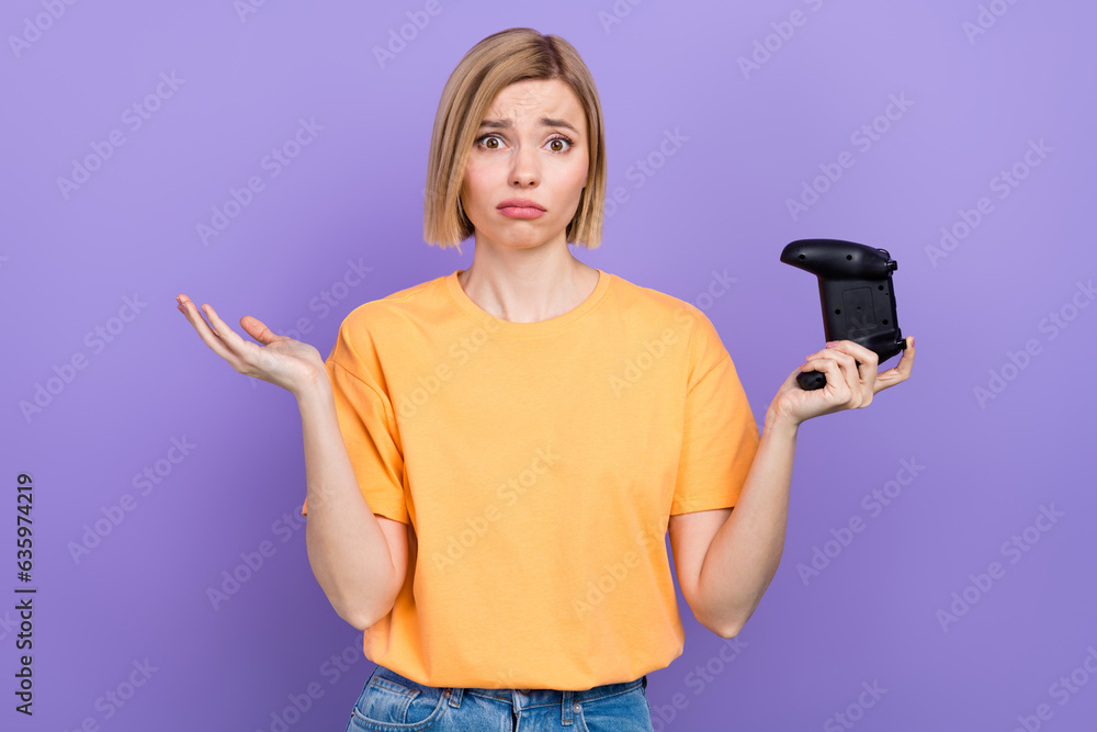 Photo of stupor young woman shrug shoulders yellow t shirt no idea how start game wireless joystick isolated on purple color background Photo of stupor young woman shrug shoulders yellow t shirt no idea how start game wireless joystick isolated on purple color background