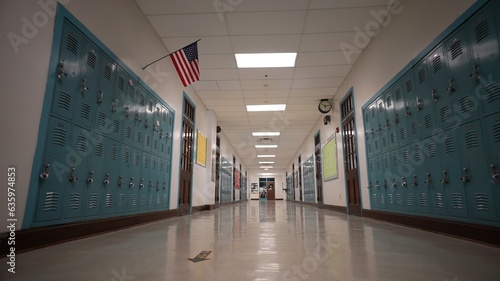 Vászonkép Low angle view down a long empty high school hallway with US American flag with the corridor lined with student lockers