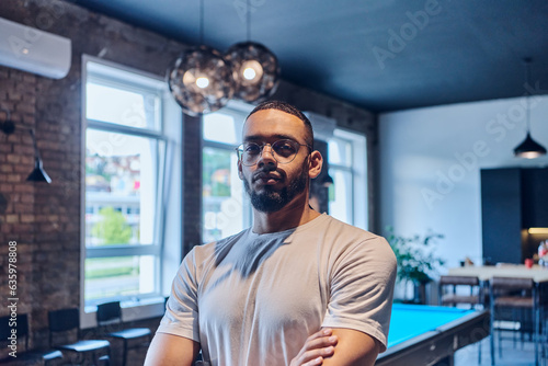 An African American businessman posing with crossed arms, exuding confidence and empowerment within the modern business setting of a startup coworking center.