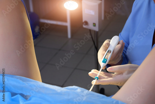Contraceptive IUD. Installation of a birth control system. The gynecologist installs an IUD. Gynecological chair. An intrauterine contraceptive device with a copper coil used for contraception.
