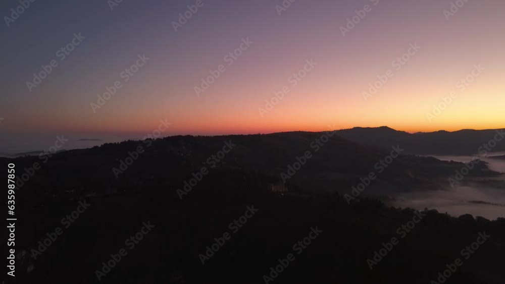 Bird's eye view of mountains covered with forests and clouds against a sea at sunset Bird's eye view of mountains covered with forests and clouds against a sea at sunset