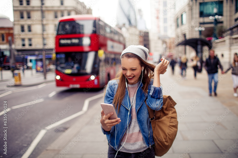 Young caucasian woman using a smart phone on a sidewalk in London UK