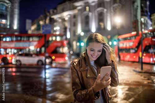 Photography Young caucasian woman using a smart phone at the Piccadilly Circus in London UK
