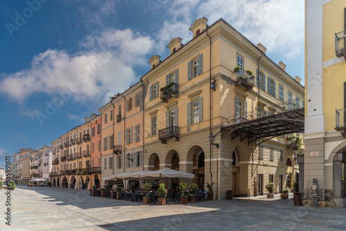 Fototapeta Naklejka Na Ścianę i Meble -  Cuneo, Piedmont, Italy - August 16, 2023: Cityscape on Roma Street main pedestrian cobblestone street with Ancient buildings decorated and with arcade in historic center