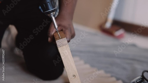 Man Drilling a screw in wooden frame during home renovation photo
