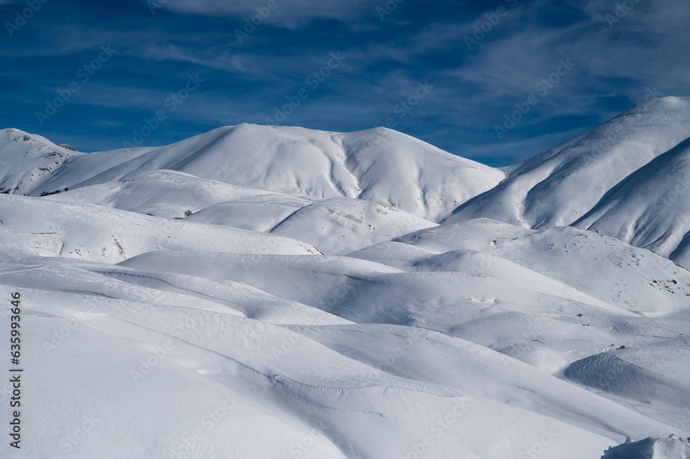 Landscape of sow covered white peaks of majestic mountains in Castelluccio di Norcia in wintertime