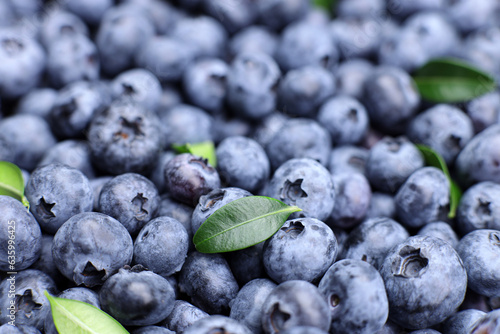 Background of fresh ripe blueberries with leaves, top view