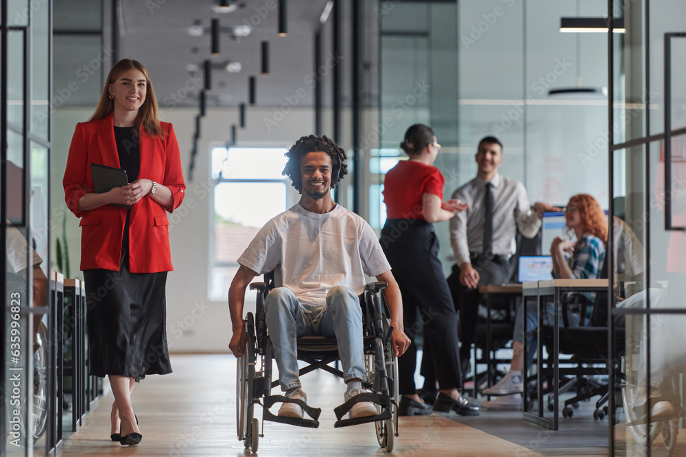 A group of young business people in a modern glass-walled office captures the essence of diversity and collaboration, while two colleagues, including an African American businessman in a wheelchair A group of young business people in a modern glass-walled office captures the essence of diversity and collaboration, while two colleagues, including an African American businessman in a wheelchair