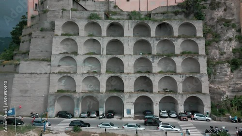 Drone shot of Wall with Arches Supportes Buildings on Rock in Tropea, Italy with beach view photo