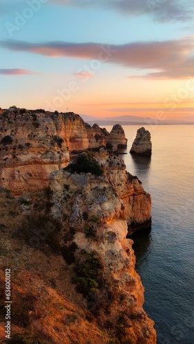 Vertical of rocky cliffs against the sea in Portugal at sunset