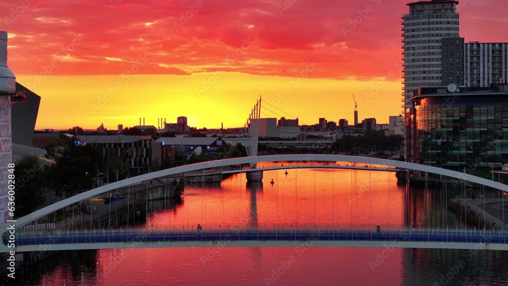 Golden sunset over a Salford Quays foot bridge, people passing by over the bridge. Golden sunset over a Salford Quays foot bridge, people passing by over the bridge.