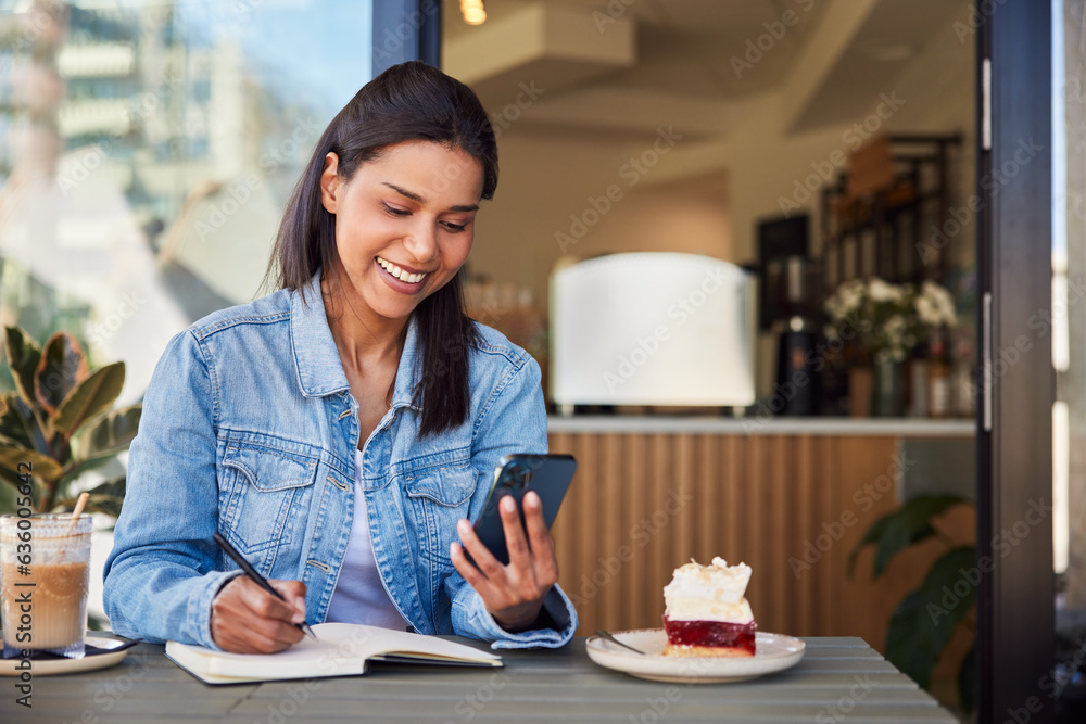 Happy female student using cellphone doing notes while in a cafe Happy female student using cellphone doing notes while in a cafe