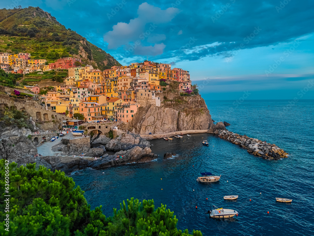 Aerial panoramic view of Manarola town with many colorful houses and bay with small boats in Cinque Terre during a sunset