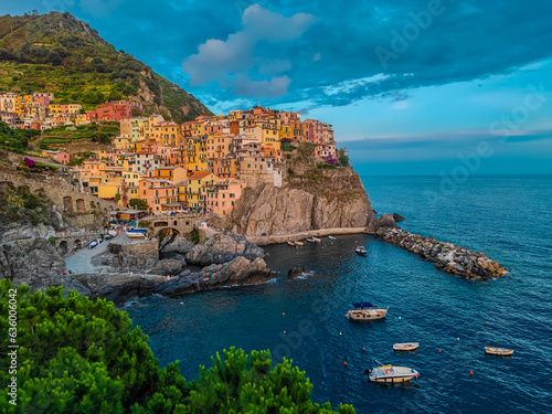 Aerial panoramic view of Manarola town with many colorful houses and bay with small boats in Cinque Terre during a sunset