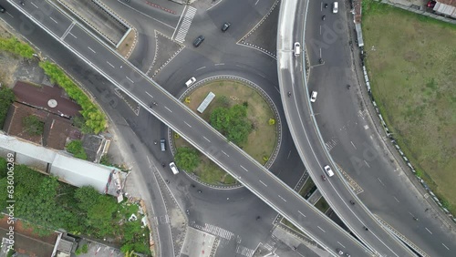 Aerial view of North Ringroad Jombor Flyover overpass in Jogja City with buildings, crowded vehicles traffic in morning sunlight. Cityscape urban landscape. photo