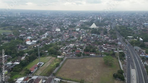 Aerial view of North Ringroad Jombor Flyover overpass in Jogja City with buildings, crowded vehicles traffic in morning sunlight. Cityscape urban landscape. photo