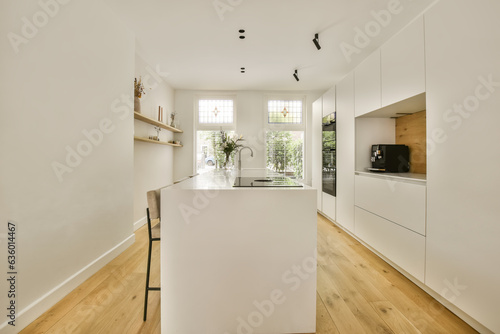 a white kitchen with wood flooring and an open door leading to the dining area in the room is well lit