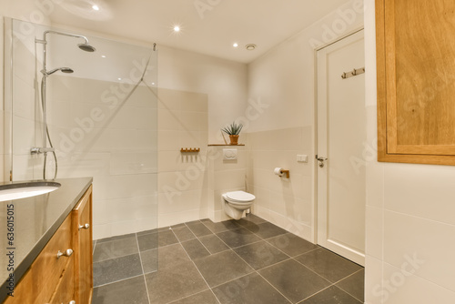 a modern bathroom with black tile flooring and wooden cabinetd cabinets in the corners on the left side