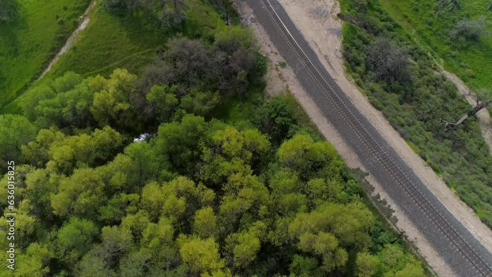 Aerial Tilt Down Shot Of Road And Railroad Track Amidst Green Plants, Drone Flying Over Natural Landscape Against Cloudy Sky - Bakersfield, California Aerial Tilt Down Shot Of Road And Railroad Track Amidst Green Plants, Drone Flying Over Natural Landscape Against Cloudy Sky - Bakersfield, California