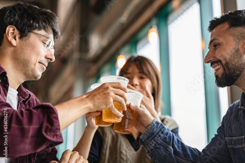 three multiracial friends in bar toasting with beers