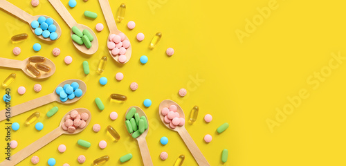 Vitamins of different colors in wooden spoons on a yellow background. Top view of scattered bright pills. Pharmaceutical industry. Health care and medicine. Pharmacy product. Copy space