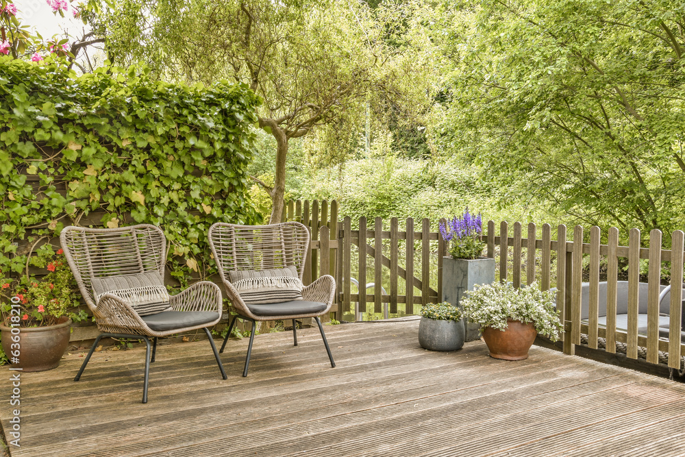 two chairs on a wooden deck in the backyard with trees and plants growing around them to create an outdoor space