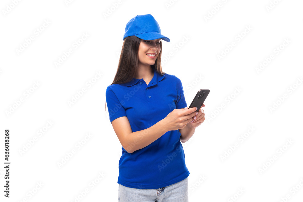 slender young brunette woman in a blue cap and t-shirt chatting in a smartphone slender young brunette woman in a blue cap and t-shirt chatting in a smartphone