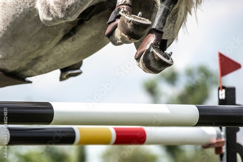 Closeup of a horse jumping over an obstacle during an equestrian show photo