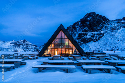 Illuminated glass building and snow covered tables in winter photo