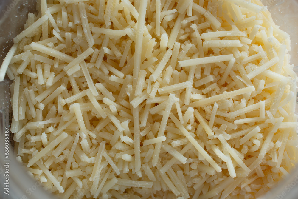 A top down view of shredded parmesan cheese inside a container. A top down view of shredded parmesan cheese inside a container.