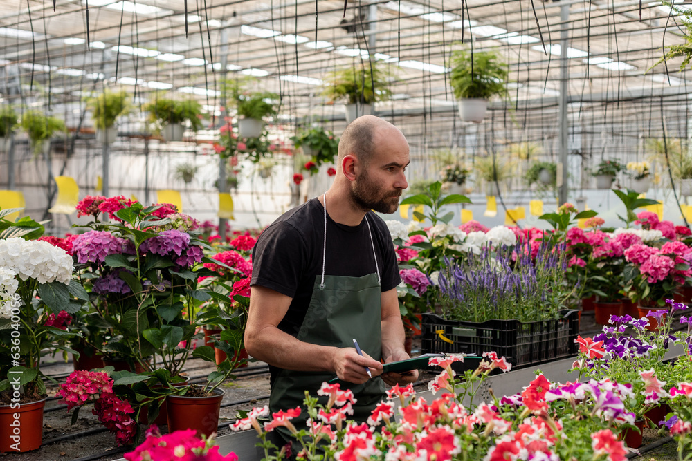 Man holds folder and pen inside greenhouse Man holds folder and pen inside greenhouse