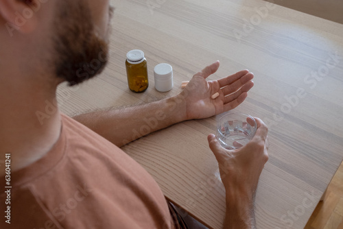 An anonymous male model is taking medications and supplements at home. photo