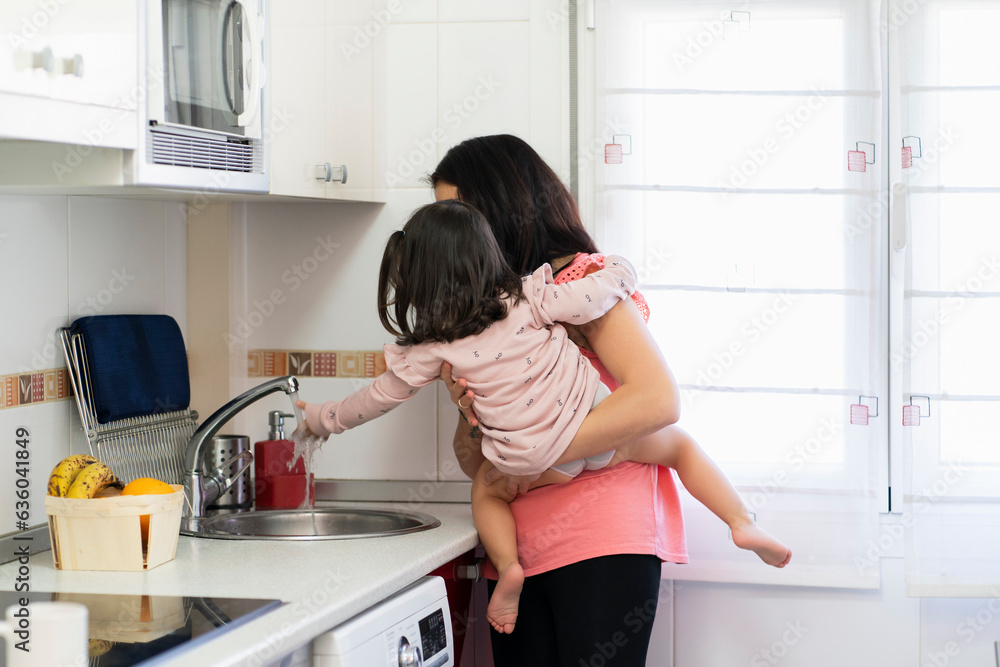 Mother and daughter washing hands in kitchen Mother and daughter washing hands in kitchen
